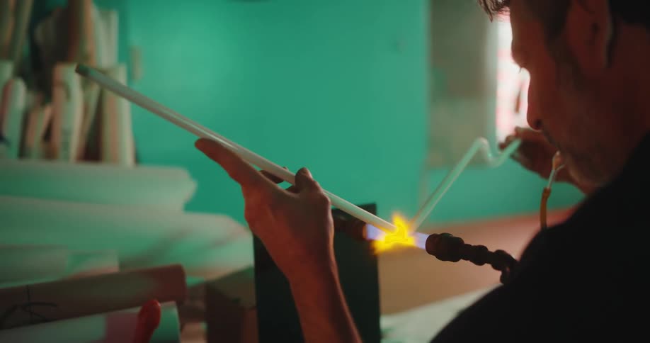 Man shaping a glass tube after heating it