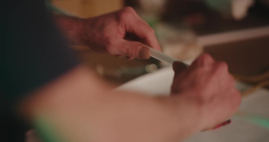 A person cutting a white pipe with a tool and underneath drawings of a blueprint of a project