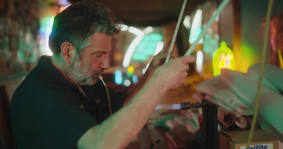 Concentrated bearded man using a blowtorch on a thin glass tube