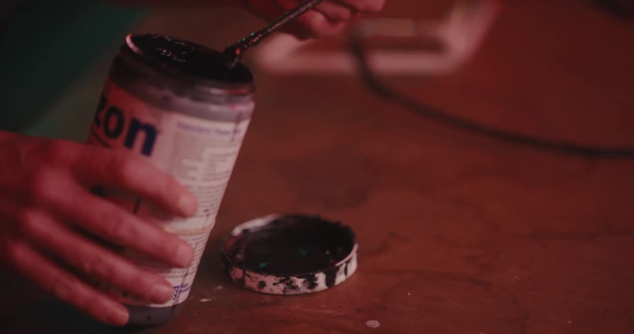 A man is mixing paint with a small brush
