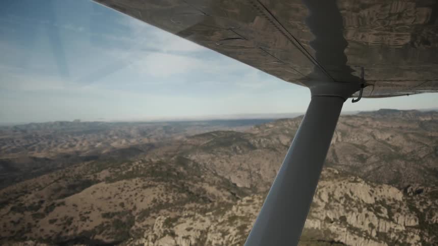 Outside of a flying plane mountain ranges can be seen below