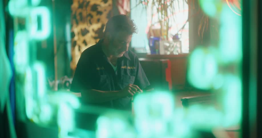 Man using his cell phone indoors with neon lights around him