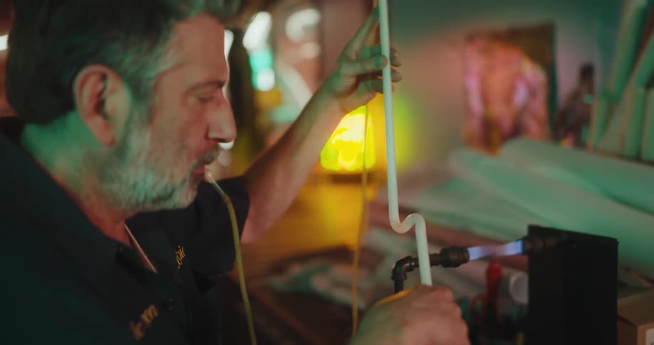 Man welding a glass tube and then placing it on a table
