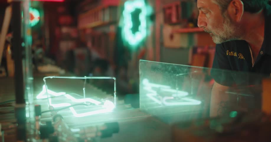 Concentrated man observing a neon light object in the shape of a lightning bolt