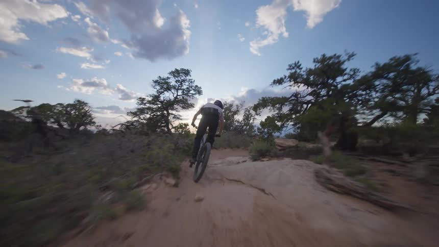 Person riding a bicycle on sandy terrain at dusk
