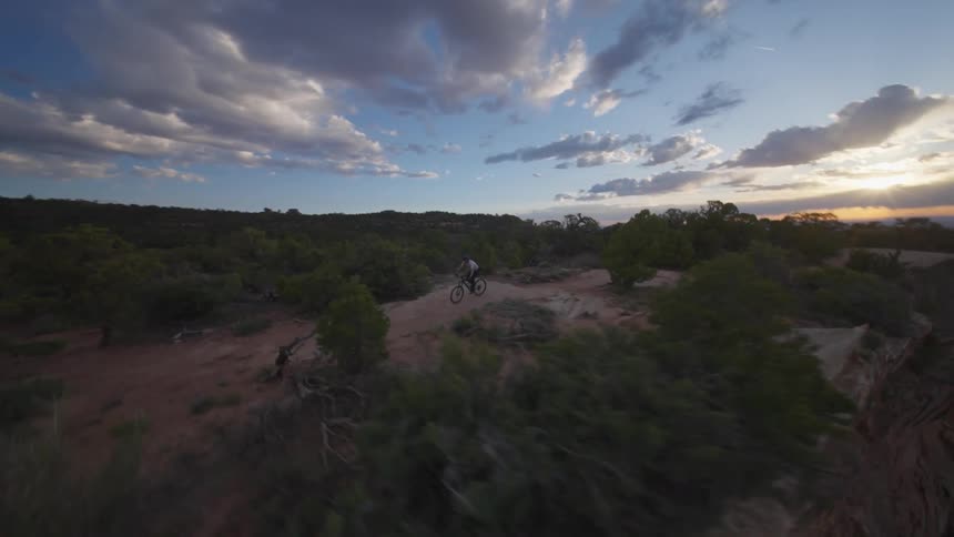 A person riding a bike on a dirt road on top of a mountain in a desert