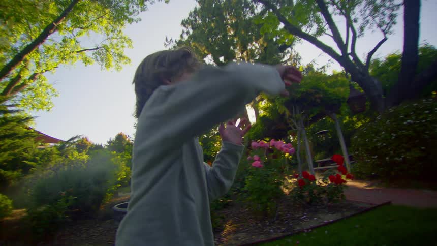 Smiling boy running in a garden with trees and flowers