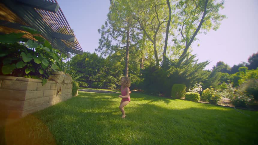 Little girl running through the grass in the backyard
