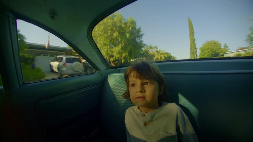 Little boy sitting in the backseat of a moving car