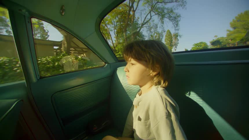 Little boy sitting in the backseat of a moving car