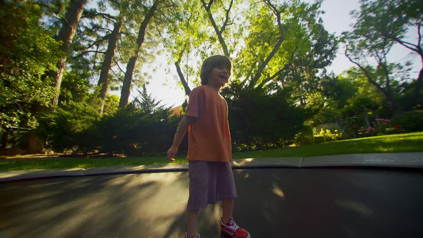 A child is jumping on the trampoline in his yard