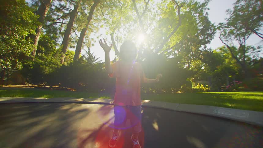 A young boy has fun jumping and falling on a ground trampoline in a yard