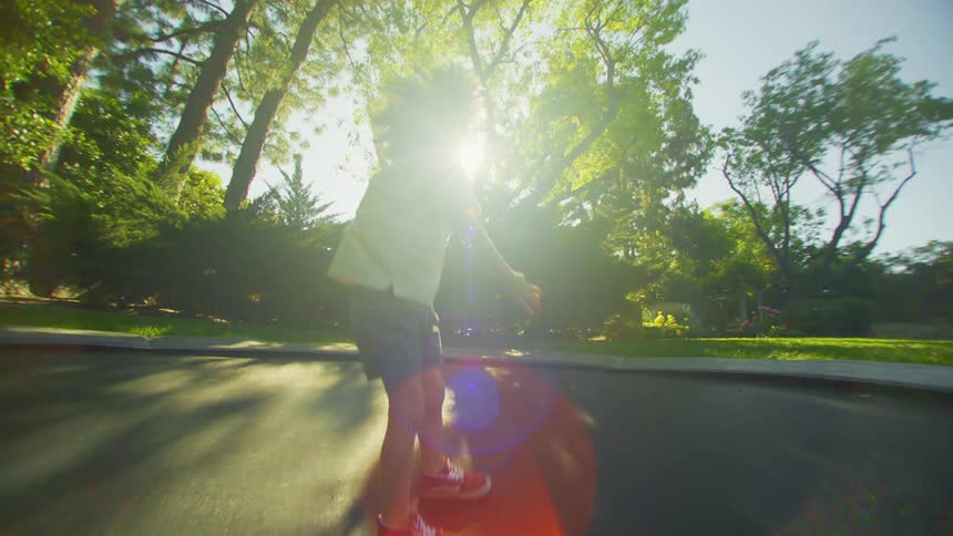 Little boy jumping on trampoline in a yard surrounded by trees