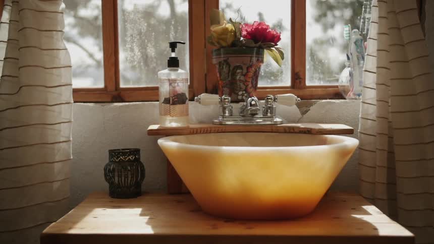The sun shines through a window and onto a bathroom basin
