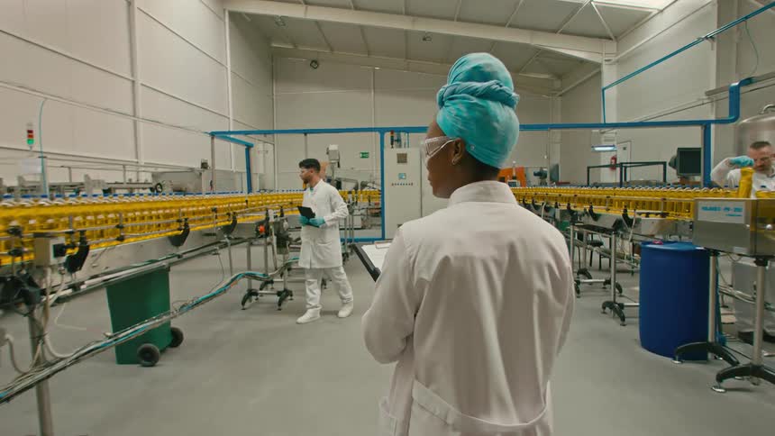 Woman carrying a clipboard consults coworker in a bottling plant