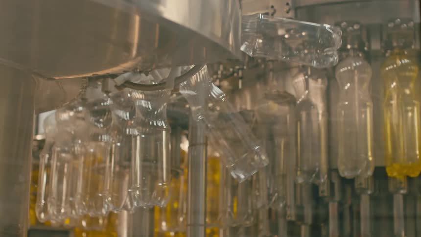 Plastic bottles filling with vegetable cooking oil on a production line