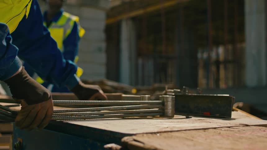 Construction worker manipulates rebar on construction site