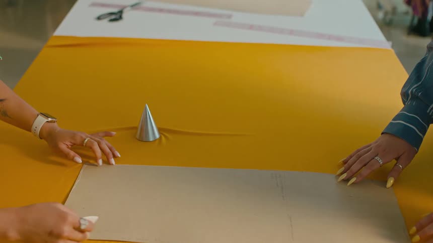 A couple of fashion designer working at a table covered with a yellow cloth