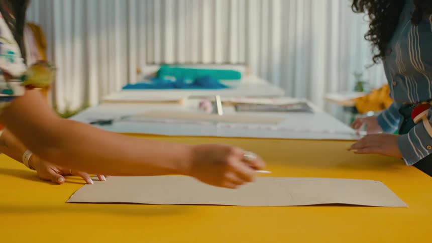 Two fashion designers drawing patterns over a yellow cloth