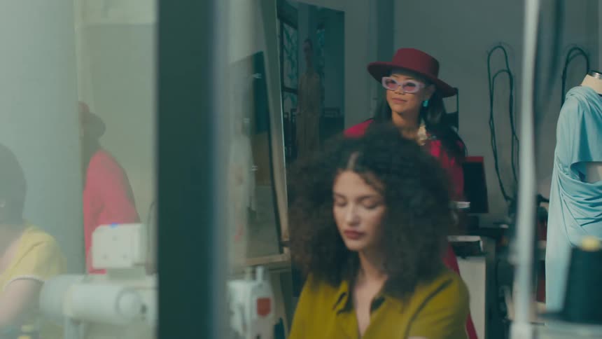 A brightly lit fashion design studio with garments and fabrics on tables
