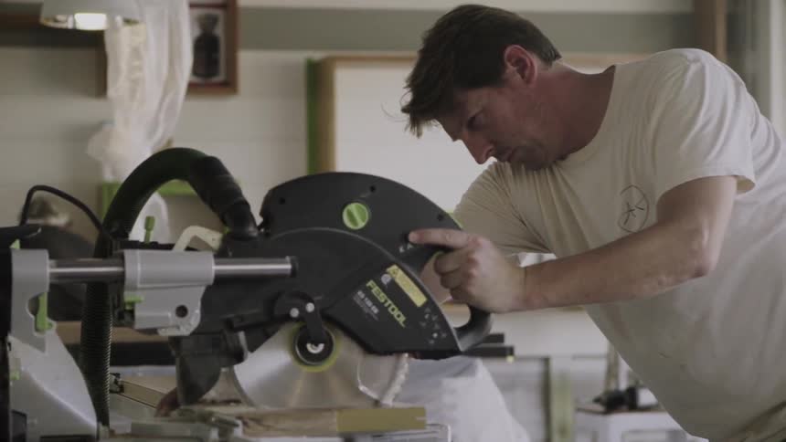 A man is cutting wood using a power saw