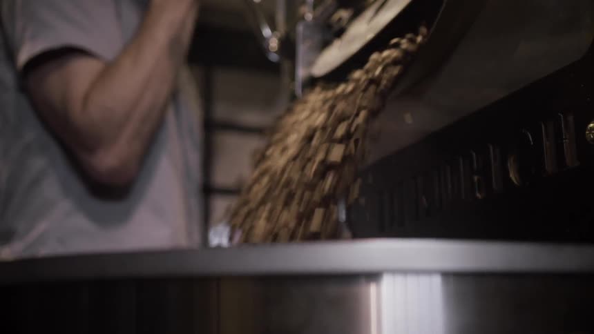 A man pushes a lever up and releases a bunch of beans into a large container