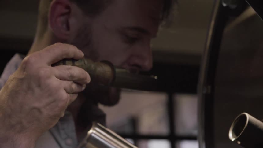 Bearded man pulling out and smelling something that's in a scoop before he places it back in place
