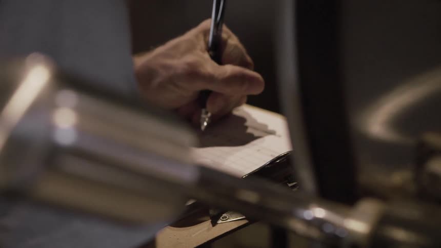 A person writes on a clipboard