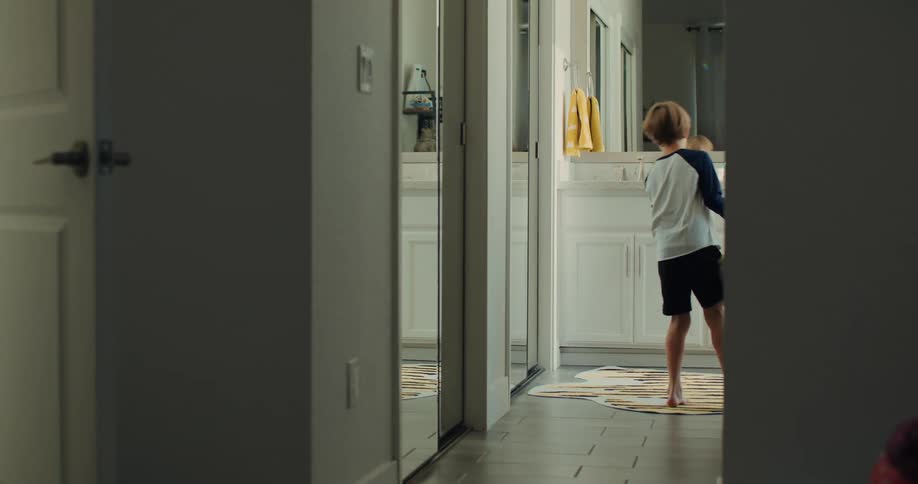 A boy walks down the hall into the bathroom
