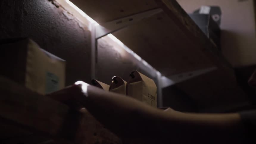 Person placing an item onto a shelf and then pushing it towards the back