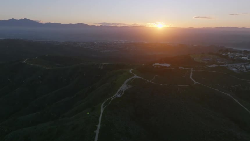 Sun sitting on red horizon shines across town on mountain plateau