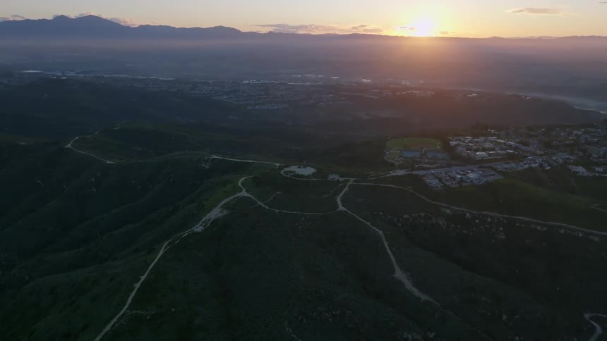 Aerial landscape of a city on hills with sunrise on the horizon