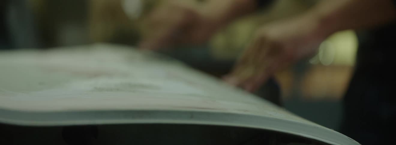 Closeup of two peoples hands with a spatula scraping a metal sheet