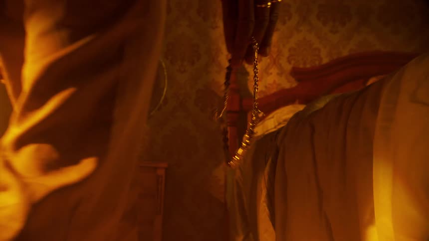 A fan spinning in a room with a bed and a person appears holding a chain and then leaves