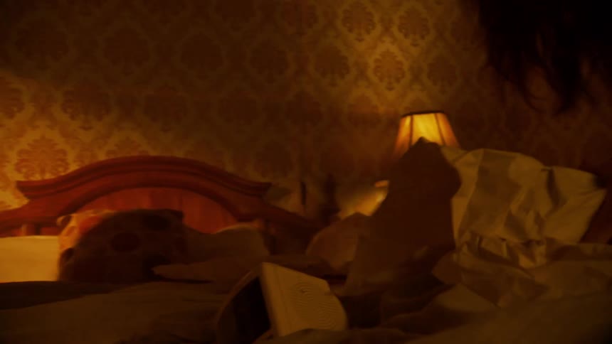 Man picks up objects from bed while woman wraps another object in paper