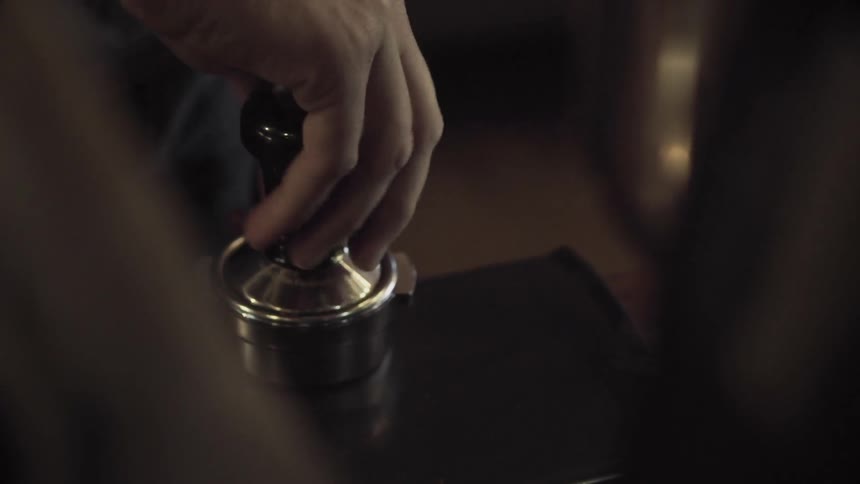Person tamping espresso in a portafilter