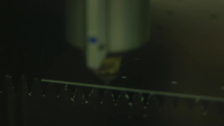Laser cuts a sheet of metal on top of a bed of triangular teeth