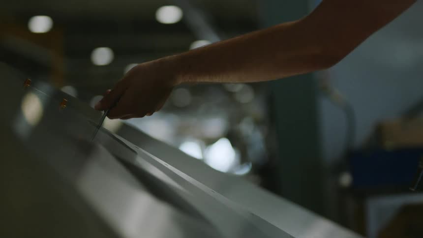 A worker adjusts a screw with a handheld machine
