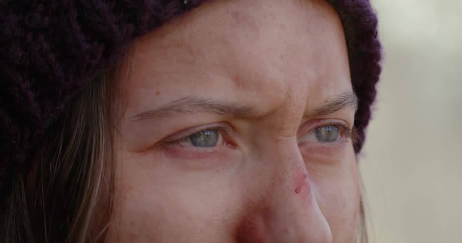 Woman with bloodstains on her face looking and using binoculars