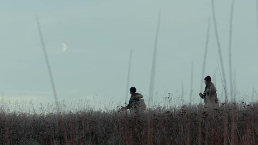 Two women running in a field on a winter day