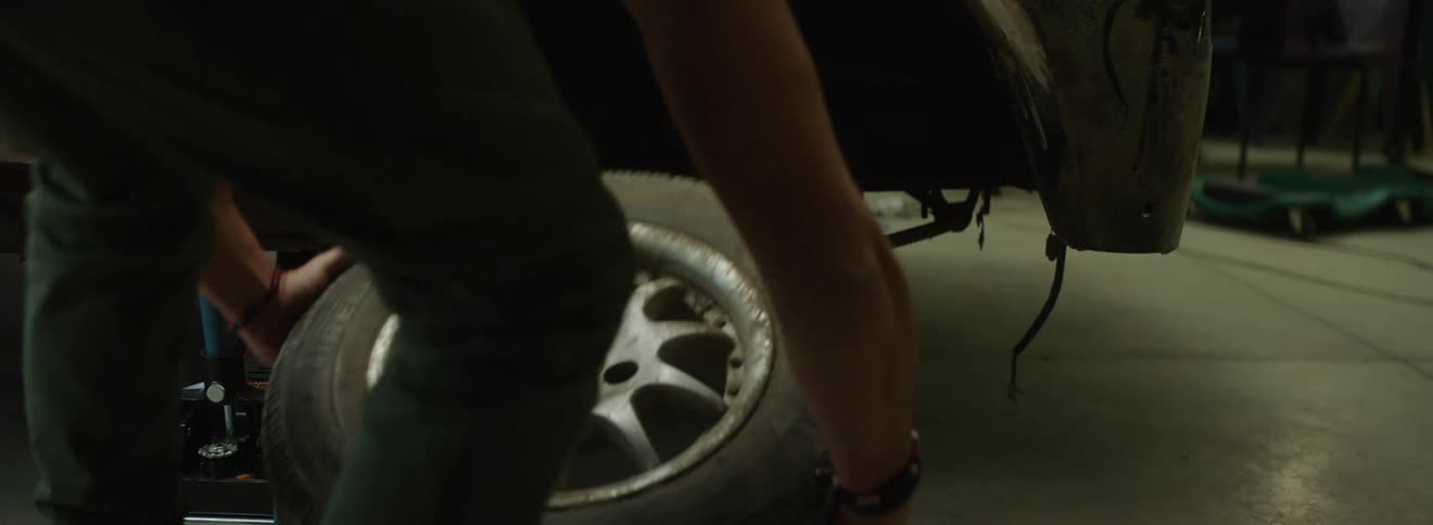 Mechanic removes a wheel from a car and places it on the ground