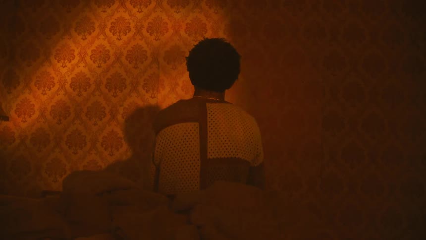 A man is sitting on the bed in the dark room