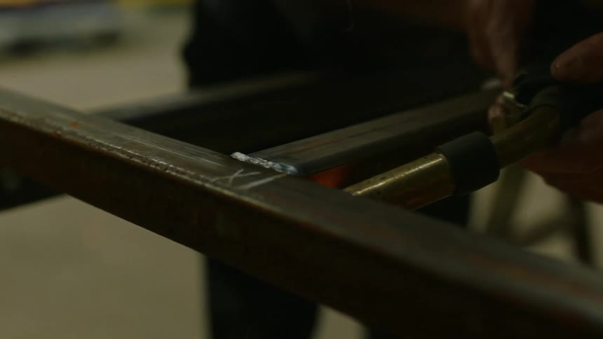 A worker spot welds a piece of metal in a workshop