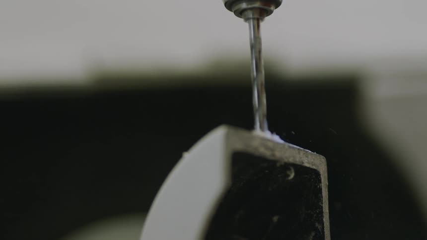 A drill drilling into a metal surface and knocking out several chips