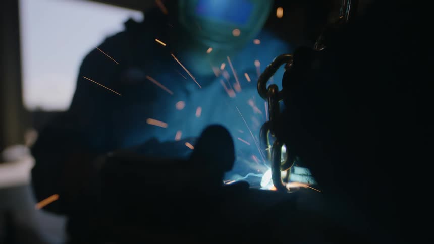 Closeup on a person working with a welding tool and sparks flying in a metalworks