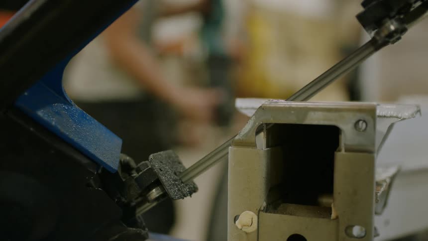 Closeup of a machine cutting a metal sheet and a person in the background