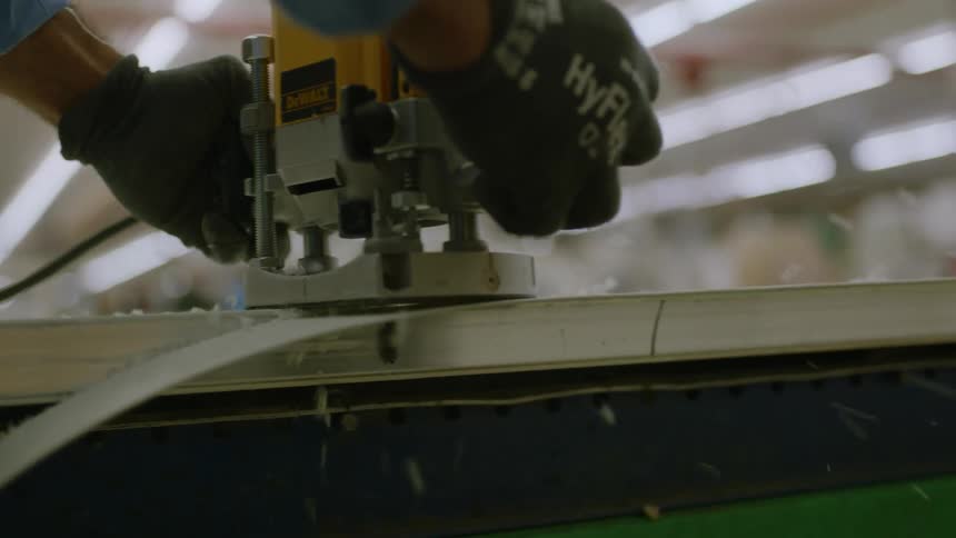 Woodworker trims the edge of a wood table with a routing tool