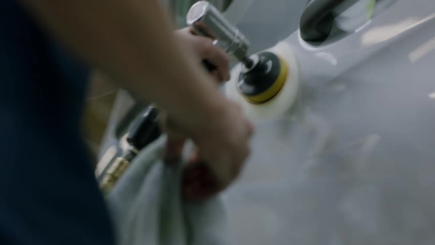 A worker polishes the side panel of a car
