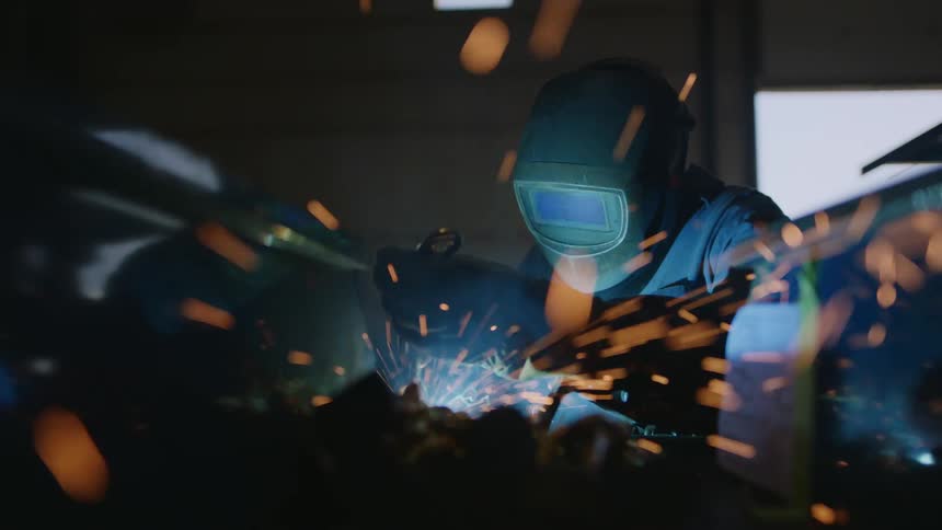 Person with protective mask carrying out welding and sparks coming out