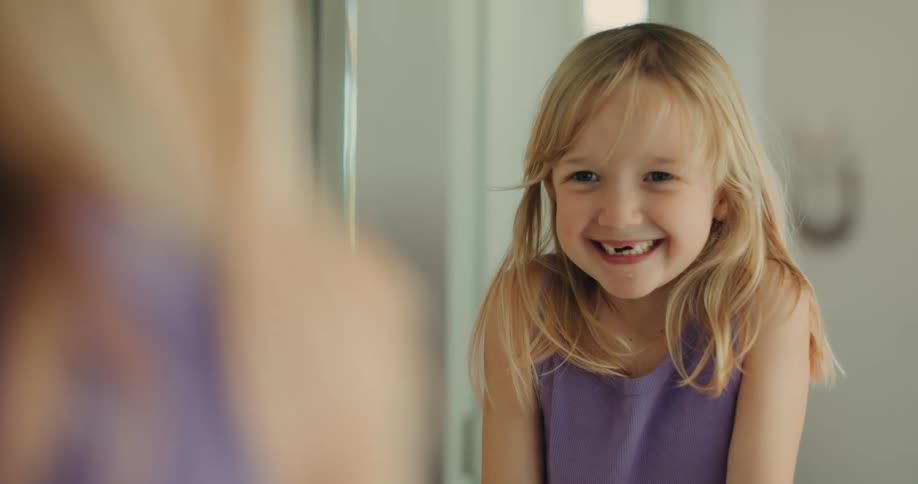 Toothless blonde girl giving a beautiful smile in front of the mirror